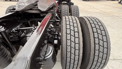 Kenworth T680 chassis showing dual rear axles and tire tread close-up, with visible drivetrain and frame components.