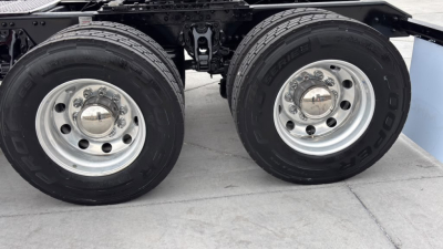 Kenworth T680 chassis with dual rear wheels showing wheel rims and tires, part of the truck's undercarriage with suspension and frame visible.