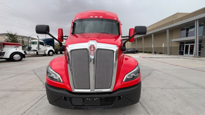 Kenworth T680 truck front view showing bold chrome grille, red exterior, and black bumper.