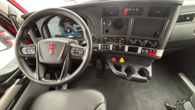 Kenworth T680 truck dash and steering wheel interior showing gauges, controls, and cup holders.