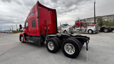 Kenworth T680 truck chassis rear view showing tandem axles and red cab.
