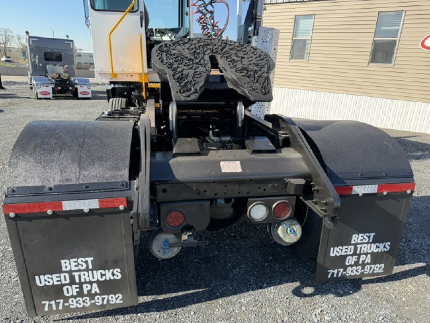 Rear view of a yard truck showing dual mud flaps with ‘BEST USED TRUCKS OF PA’ and contact numbers, visible hydraulic lines and hitch area.