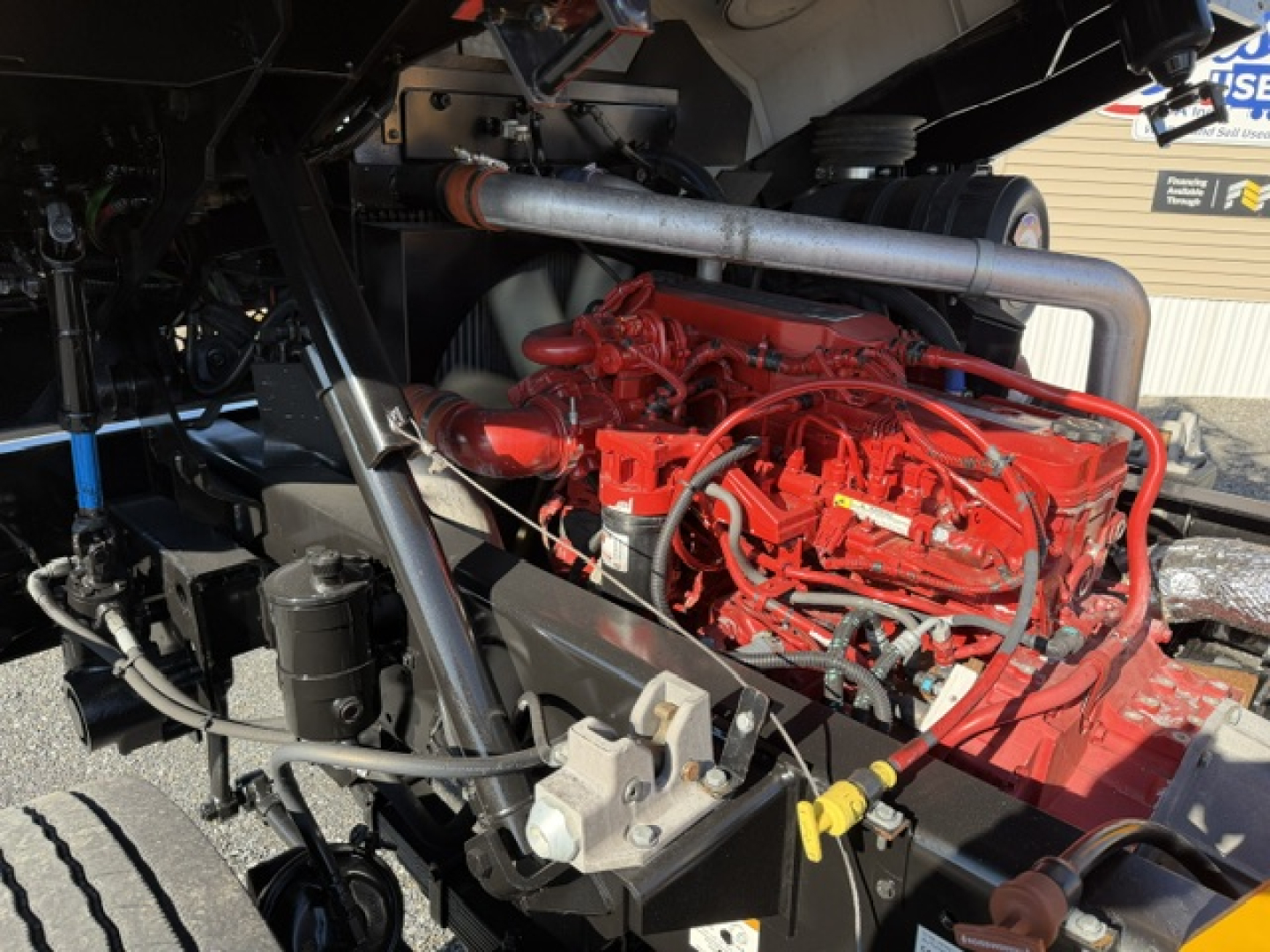 Capacity Sabre engine bay showing red diesel engine with hoses and metal exhaust pipe, chassis framing, and coolant reservoir.