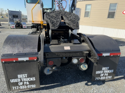 Rear view of a yard truck showing dual mud flaps with ‘BEST USED TRUCKS OF PA’ and contact numbers, visible hydraulic lines and hitch area.