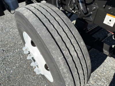 Truck wheel and suspension area with tire tread and part of chassis visible.