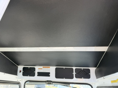 Trailer interior ceiling and wall with vent panels and warning labels; metal framework with perforated panels.