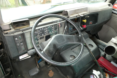 Cab interior of a 1997 International 8100 truck showing steering wheel, dashboard gauges, and driver controls.