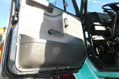 Truck cab interior door panel of a 1997 International 8100 daycab, with steering wheel and dashboard visible in background.