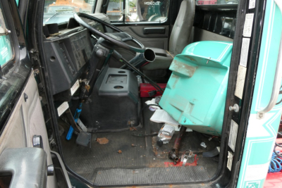 Interior of a 1997 International 8100 cab showing dashboard, steering wheel, and a turquoise fuel container in the passenger area.