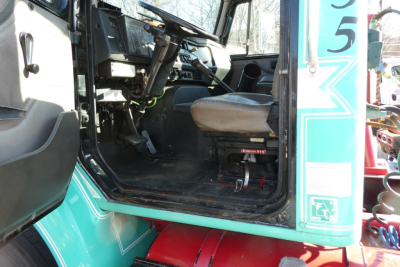 Interior of a truck cab with steering wheel and seat visible; open driver’s door on teal International 8100 with red steps.