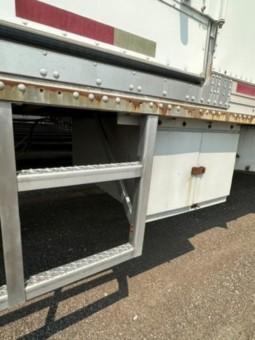 Trailer frame with metal steps and undercarriage, side of refrigerated trailer showing riveted aluminum panels and storage box.