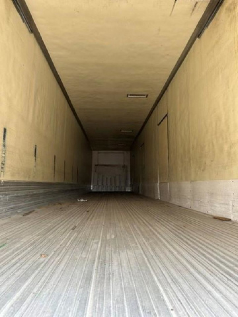 Trailer interior showing empty refrigerated cargo space with ribbed floor and light at ceiling.