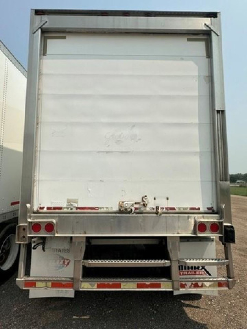 Rear view of a white refrigerated trailer with doors closed, showing undercarriage, taillights, and bumper ridges.