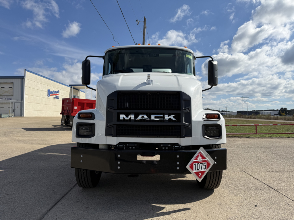Mack MD7 truck front view showing large black grille with MACK letters, white cab, bumper, and hazard placard 1075 on lower right front.