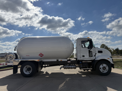 Semi-truck with cylindrical tank mounted on trailer, white cab, empty background, side view showing tank and chassis.