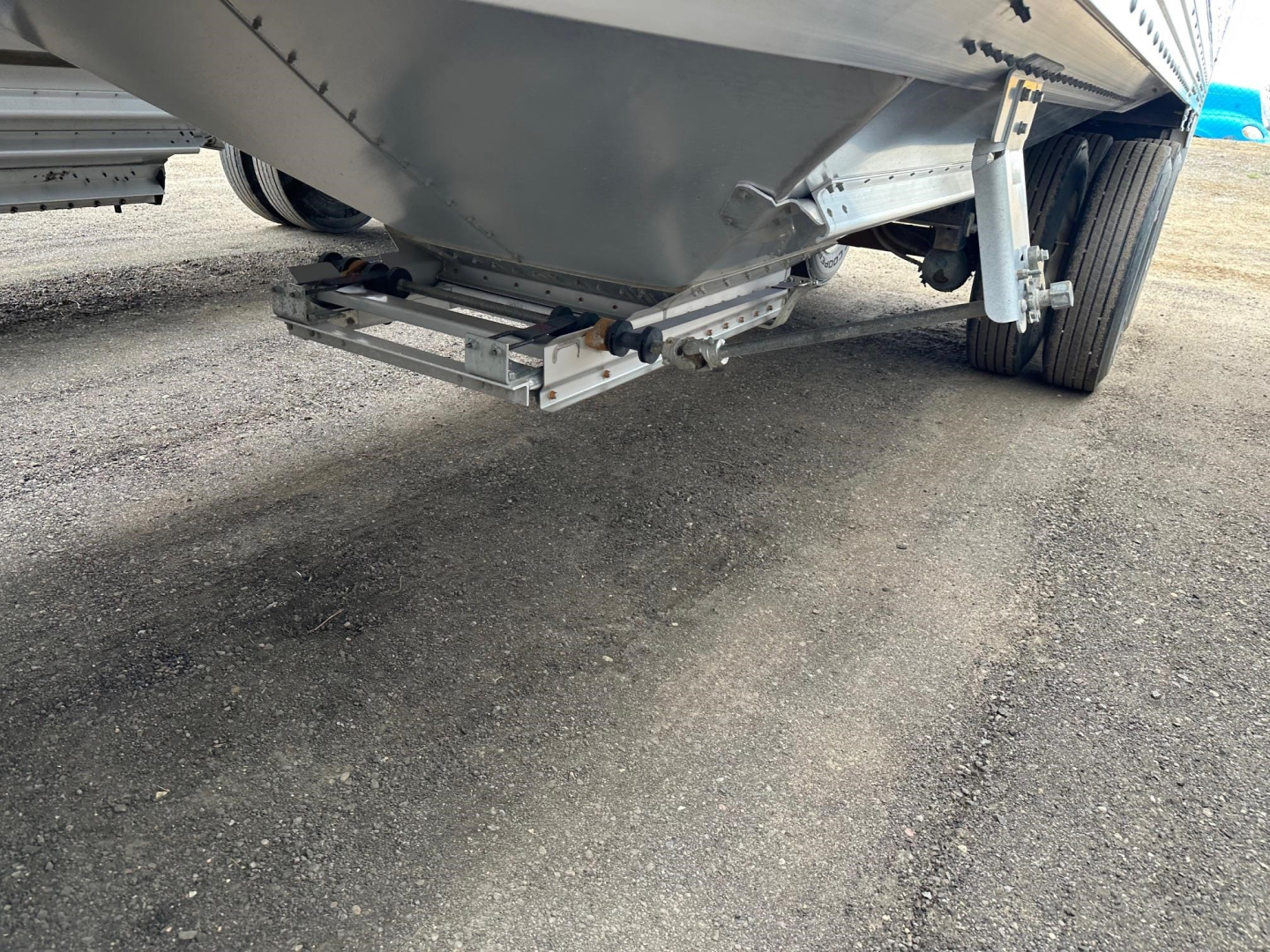 Trailer underside showing hitch and lower frame of a Timpte Super Hopper W hopper trailer with metal brackets and wheels in view.