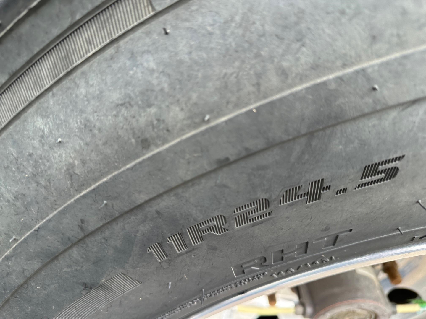 Tire sidewall showing 12.4.5? and load rating markings, with tread and rim visible.