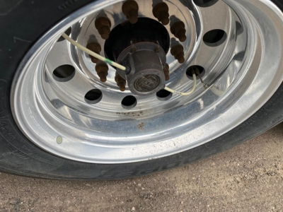Trailer wheel hub with polished steel rim and lug nuts visible; close-up view of a hub area on a used hopper trailer.