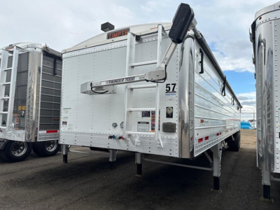 Timpte Super Hopper trailer in a yard, side and rear view, with the model badge and loading hopper visible.