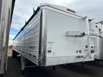 Trailer side and rear of a used 2024 Timpte Super Hopper aluminum agricultural trailer with reflective panels and rear loading mechanism.