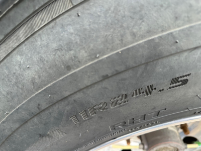 Tire sidewall showing 12.4.5? and load rating markings, with tread and rim visible.