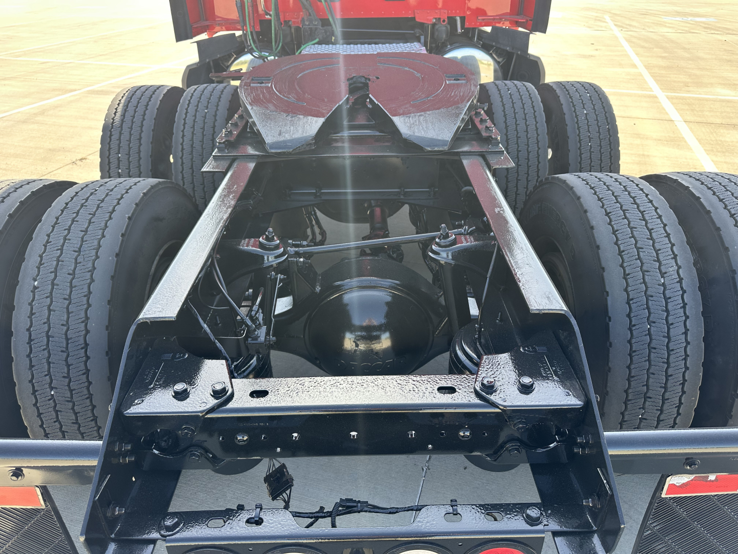 Kenworth T680 chassis rear view showing dual rear axles and fifth wheel mounting; visible frame rails, suspension components, and drive axles.