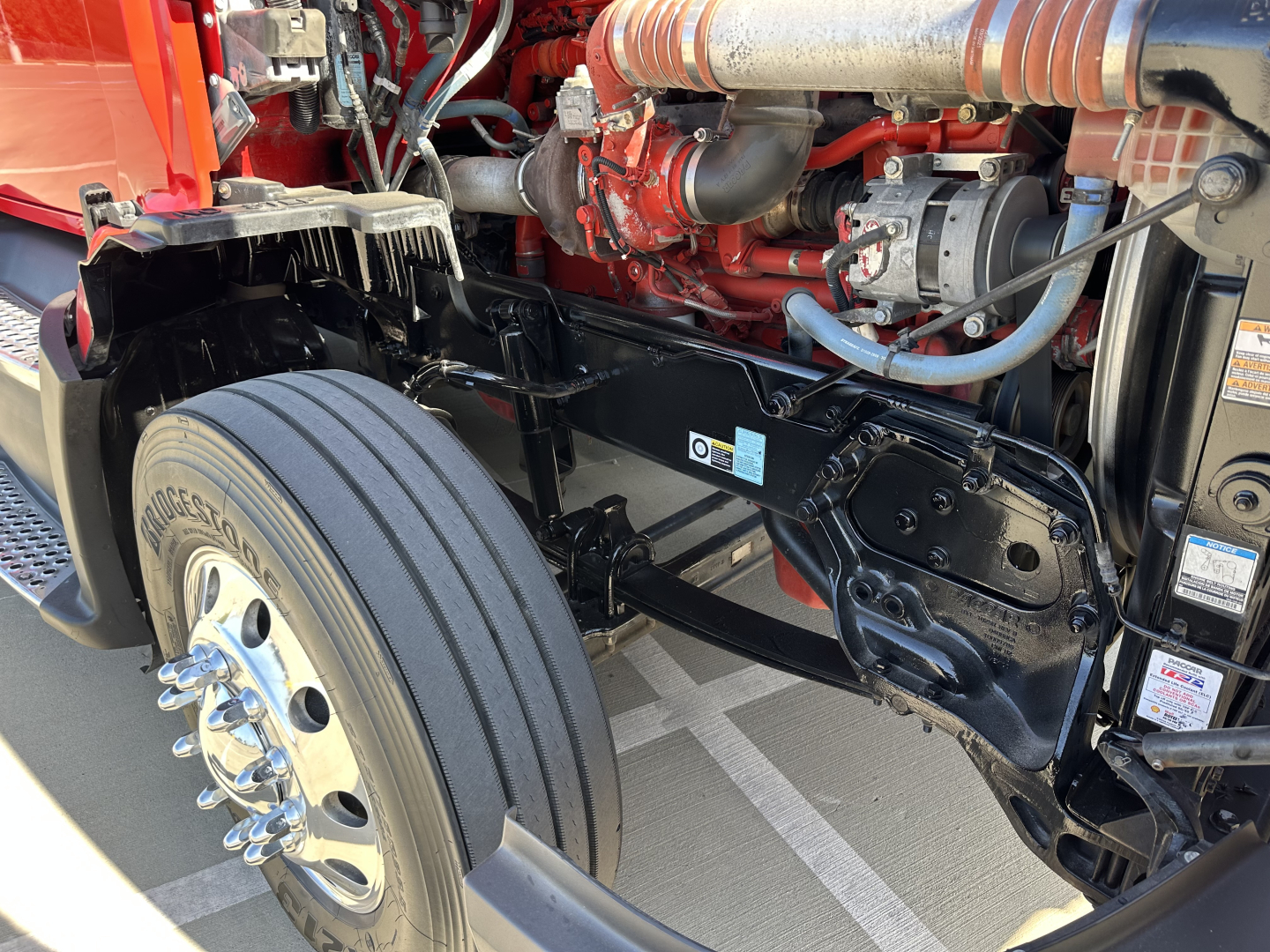 Kenworth T680 front chassis and engine bay showing suspension, twin I-beam frame, and front axle with Bridgestone tire.