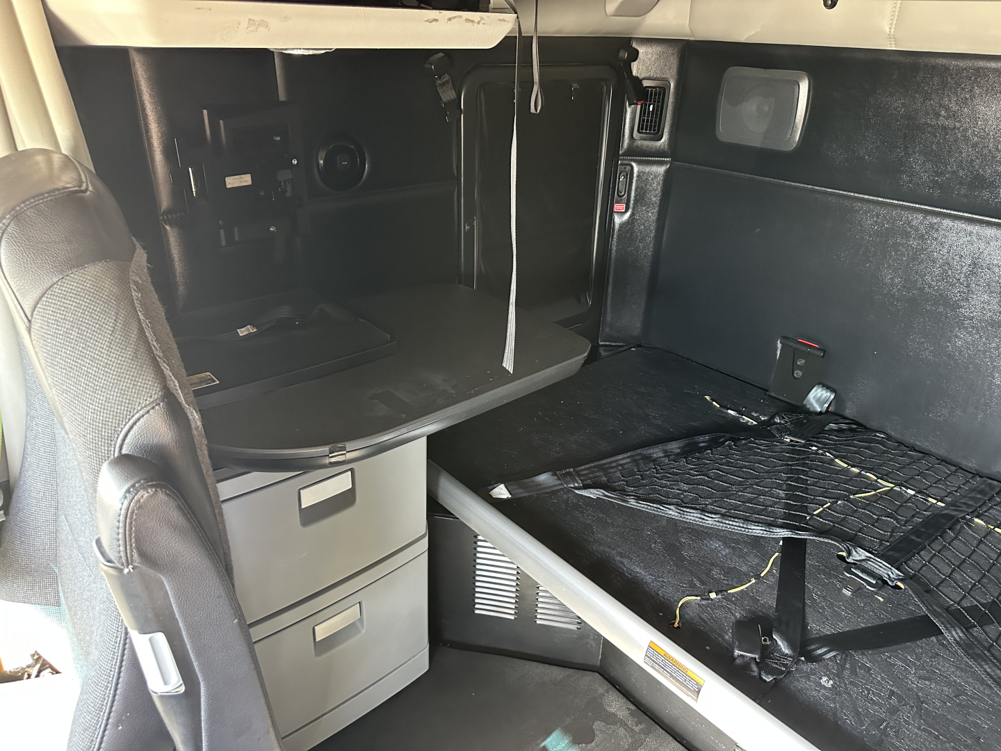 Kenworth T680 sleeper cab interior showing bed area, storage drawers, and overhead compartments with cables.