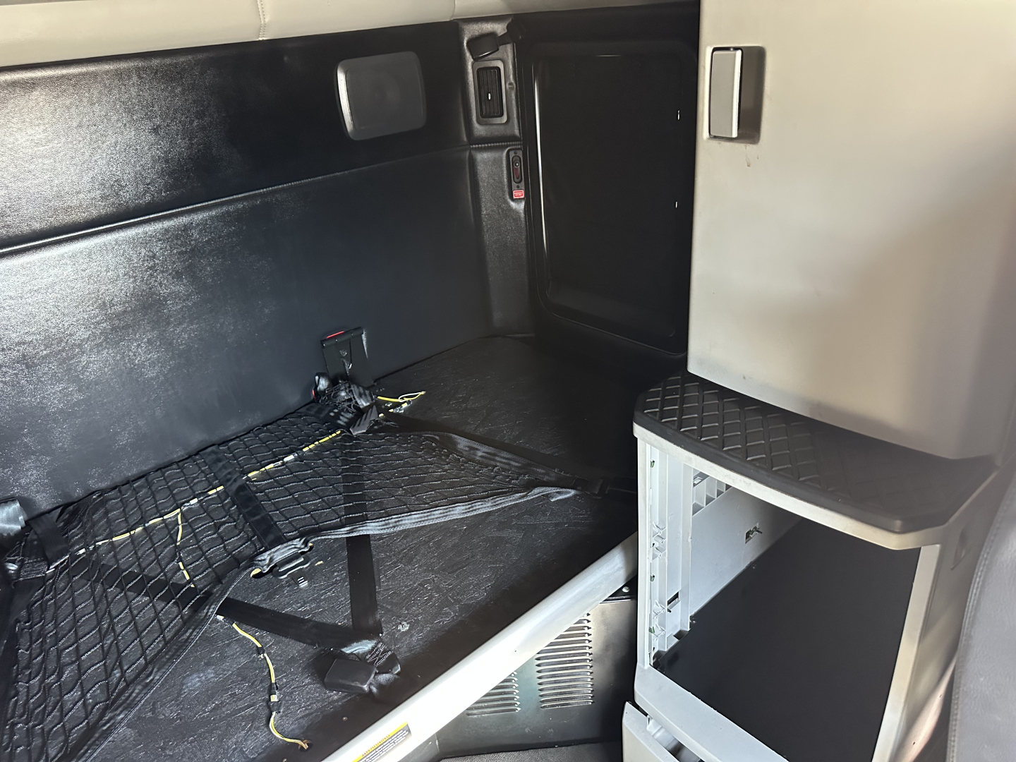 Kenworth T680 sleeper cab interior cargo area showing net cargo strap and side storage shelf.