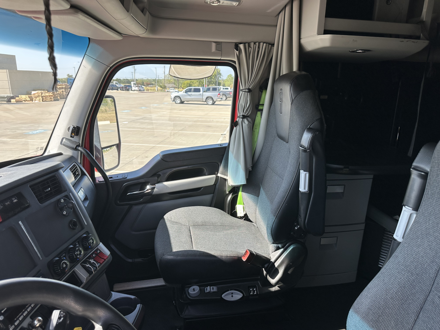 Kenworth T680 interior cab view showing driver seat and dashboard; window view outside.