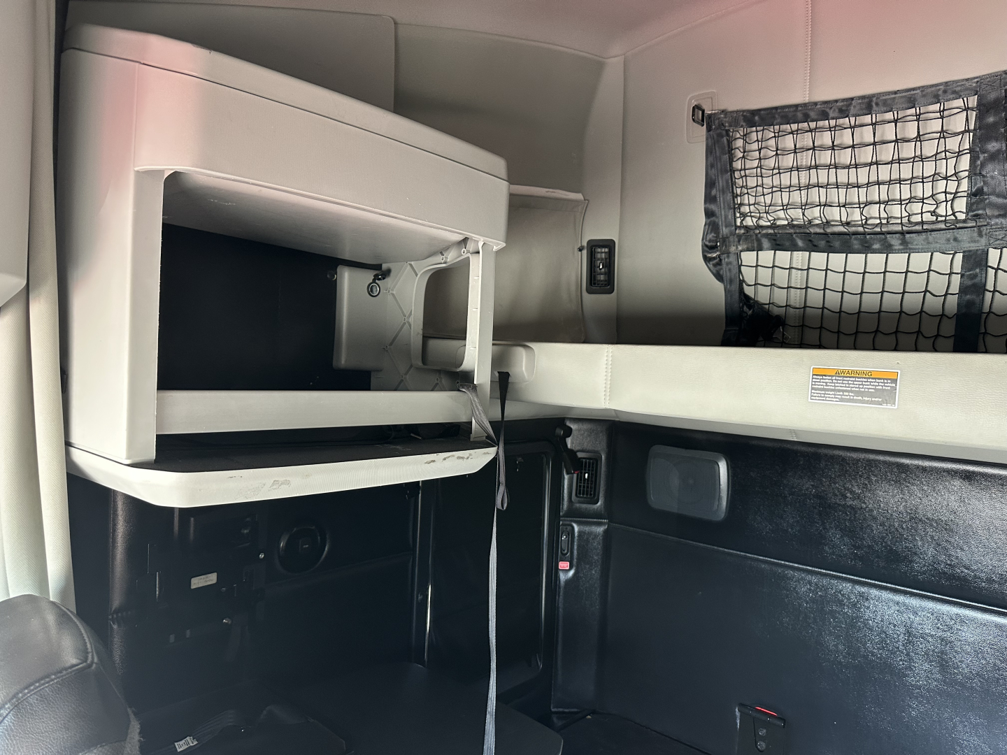 Kenworth T680 sleeper cab interior showing overhead dash with storage shelf and a hanging net pocket.