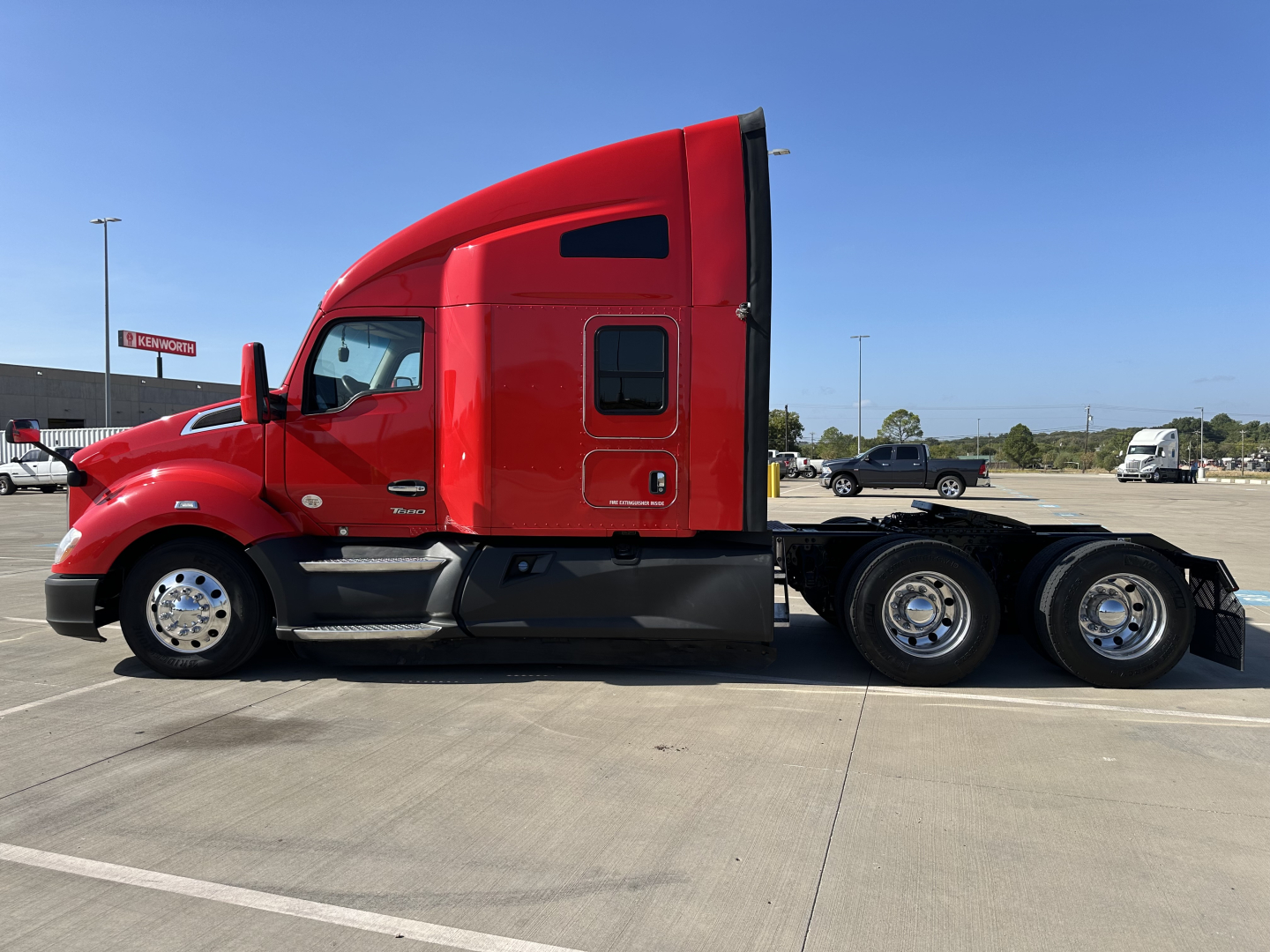 Kenworth T680 tractor side view showing red sleeper cab and rear wheels.