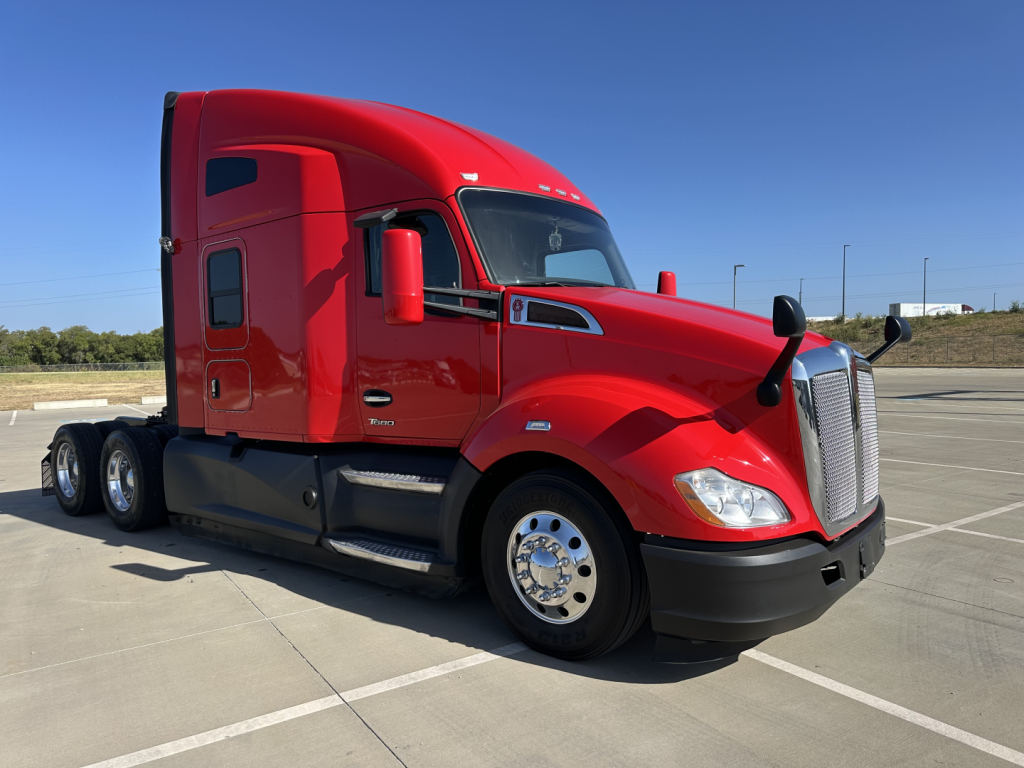 Kenworth T680 in red showing side profile with sleeper cab and chrome wheels.