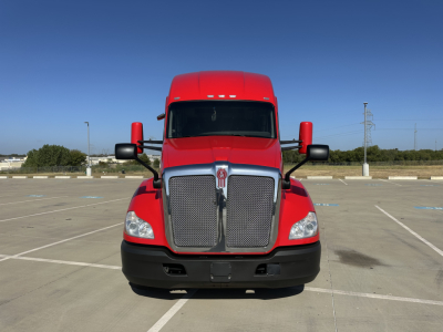 Kenworth T680 front view showing large chrome grille and red cab with black bumper and side mirrors