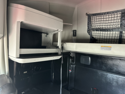 Kenworth T680 sleeper cab interior showing overhead dash with storage shelf and a hanging net pocket.