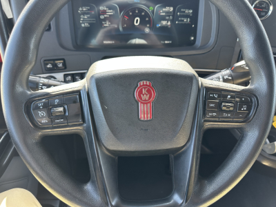 Kenworth T680 steering wheel with KW emblem and dashboard controls visible in view from driver seat.