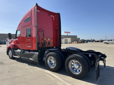 Kenworth T680 side view showing triple-axle rear with red cab and exposed chassis.