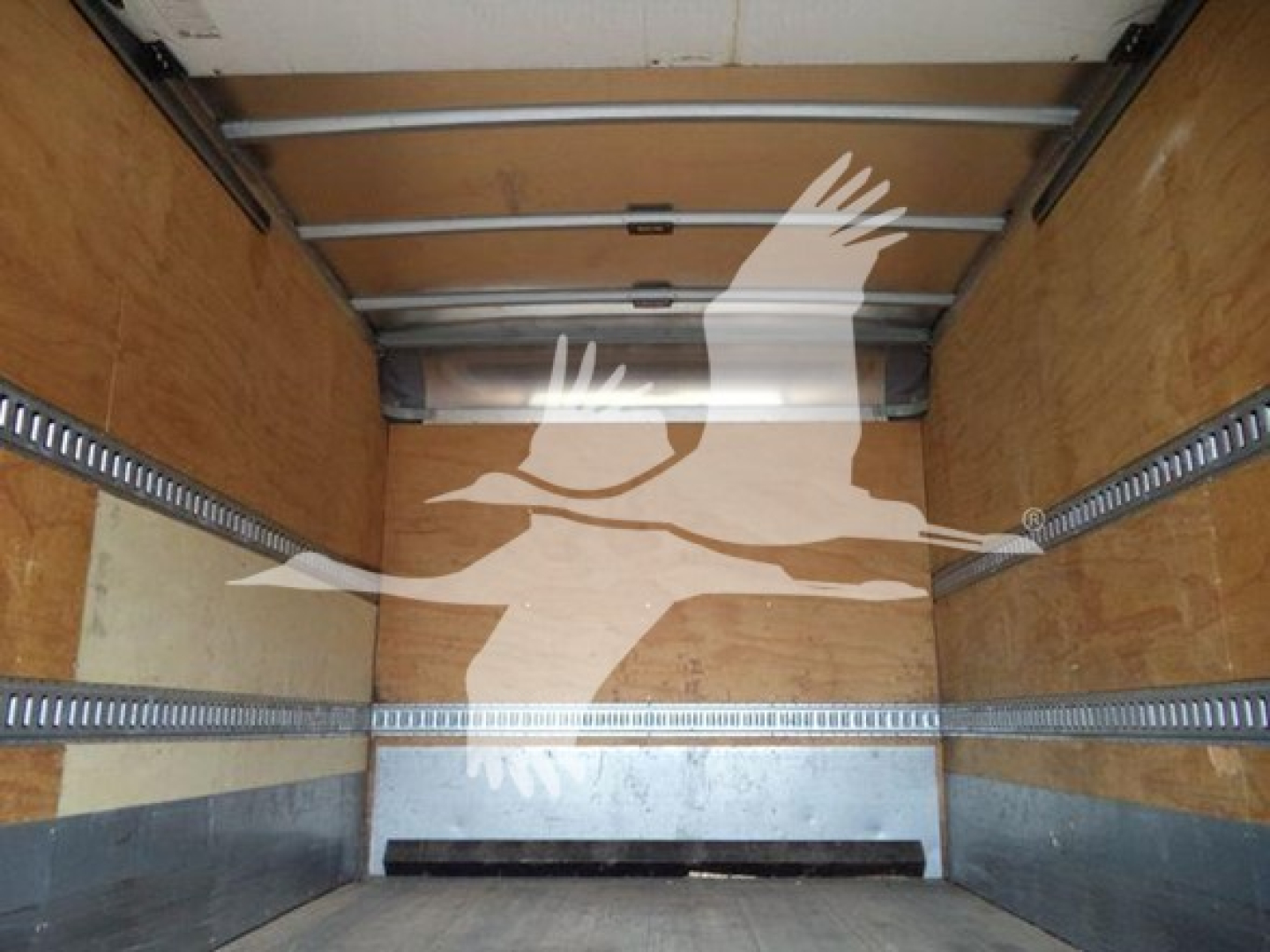 Isuzu NQR truck box interior showing wooden walls and metal E-track rails, empty cargo area with rear door tracks visible.