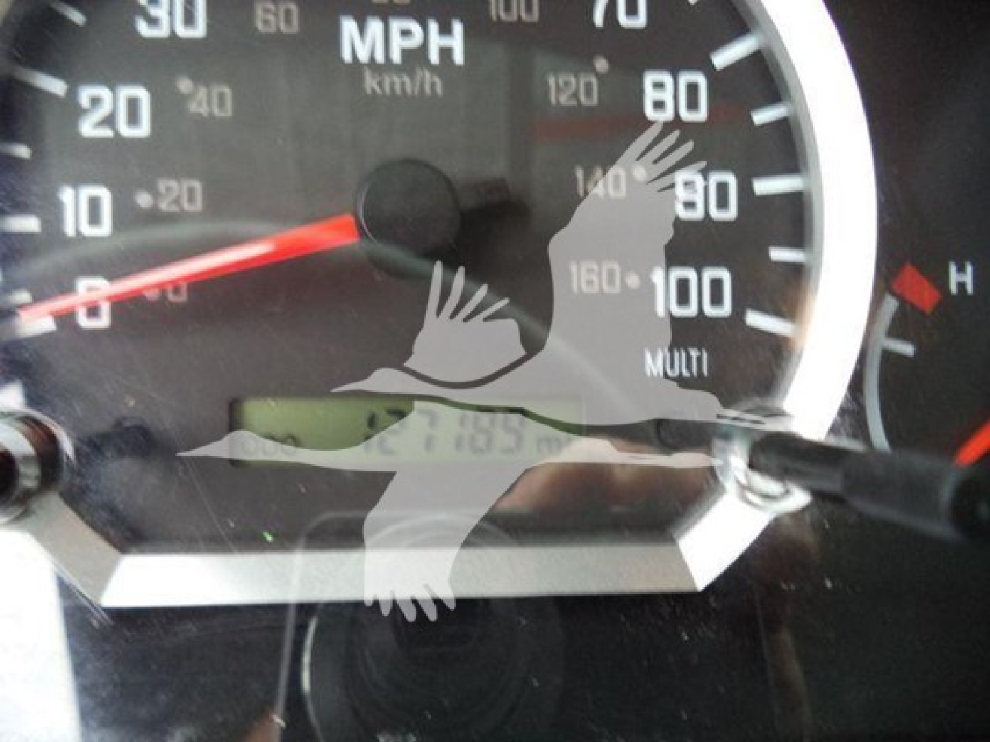Isuzu NQR dashboard showing speedometer with speed in mph and km/h, partial odometer display, and a reflection overlaid on the gauge area.