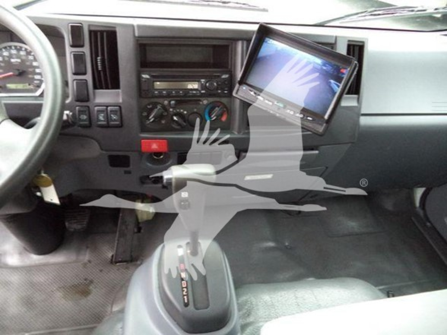 Isuzu NQR cab interior with dashboard, gear shifter, and a mounted tablet display showing vehicle controls.