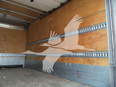 Truck cargo area with wooden side panels and metal rails; large white bird graphic on the side wall.