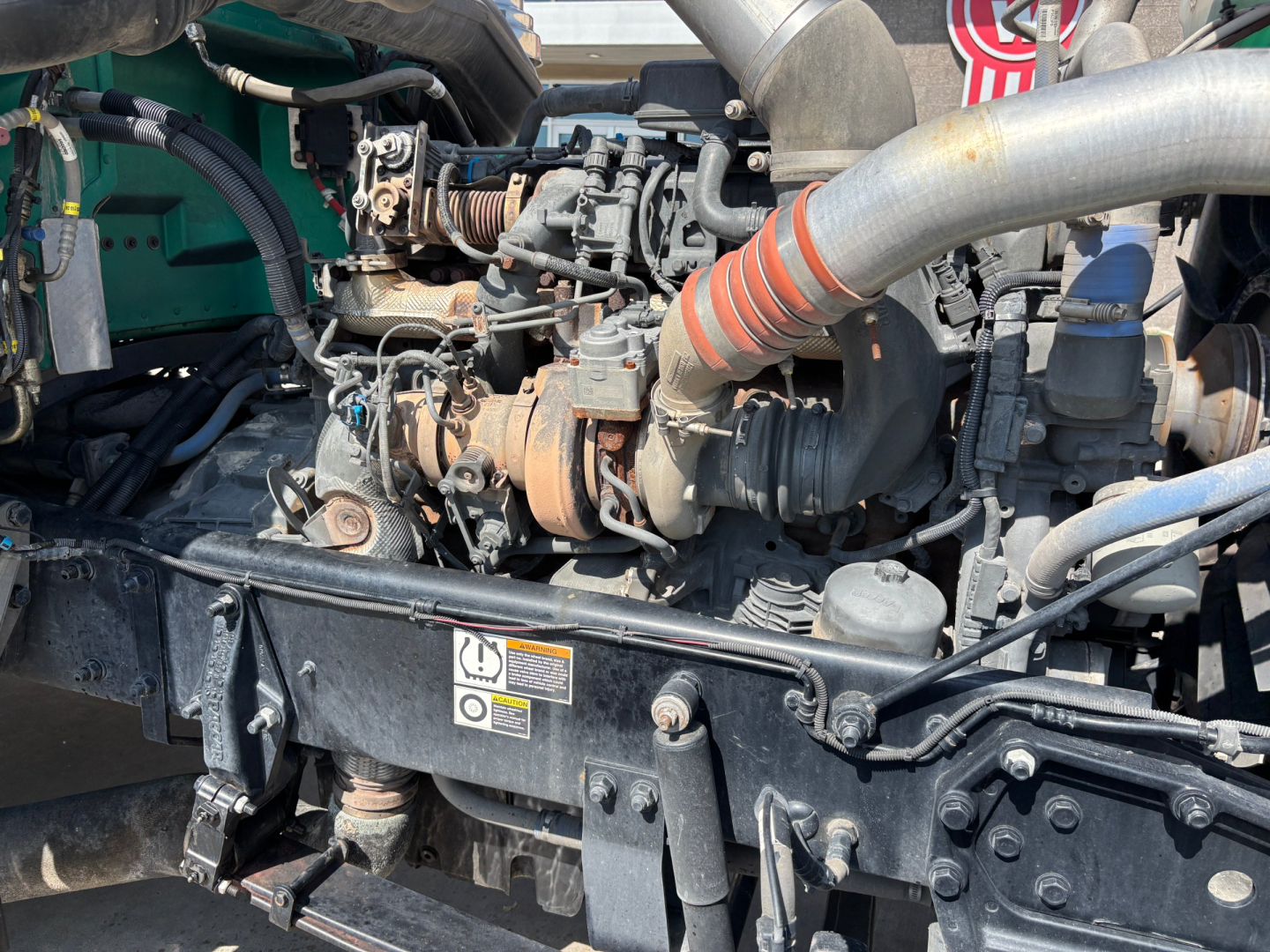 Peterbilt 389 engine bay showing intake manifolds and turbocharger with hoses and wiring visible.