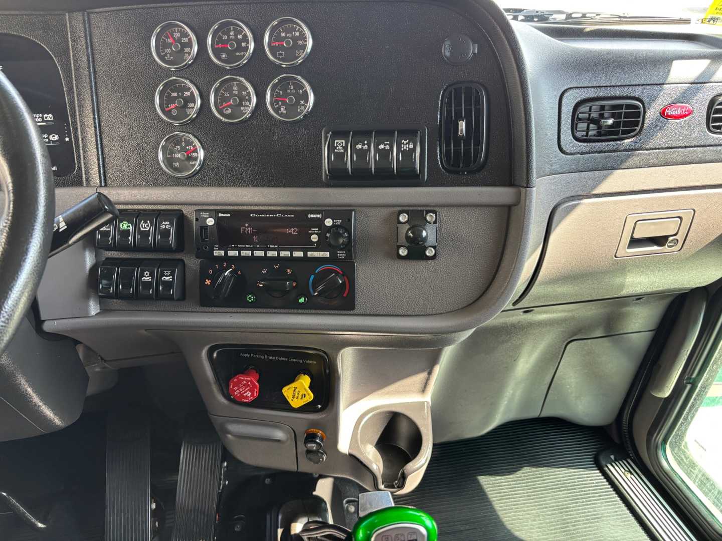 Peterbilt 389 interior dashboard with multiple gauges, switches, climate controls, and cup holder area.
