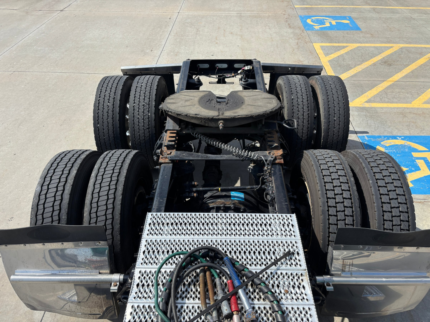 Peterbilt 389 tractor rear view showing chassis, dual rear axles with six wheels, metal perforated step, and wiring harnesses on the frame.