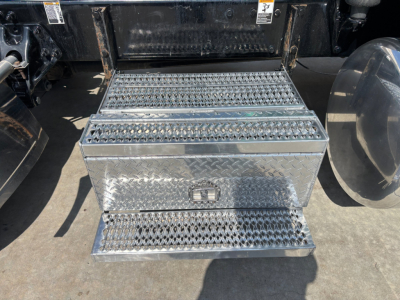 Truck access step and storage box under Peterbilt 389 cab with diamond plate metal steps and storage chest.