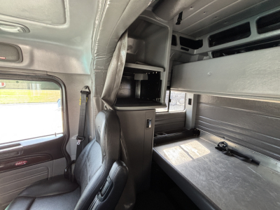 Peterbilt 389 cab interior with sleeper compartment, overhead storage, and a metal bunk/console area visible.