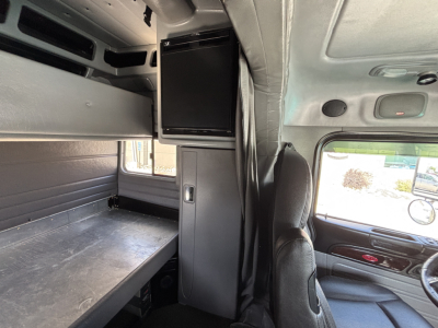 Peterbilt 389 sleeper cab interior showing bunk area and overhead console with a mounted monitor in view