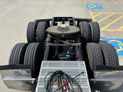 Peterbilt 389 tractor rear view showing chassis, dual rear axles with six wheels, metal perforated step, and wiring harnesses on the frame.