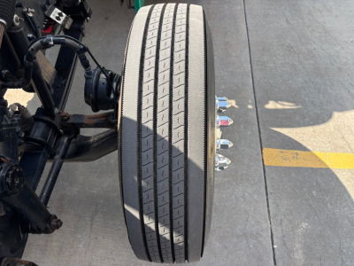 Wheel assembly and dual rear axle components of a Peterbilt 389 truck showing a large front tire and air suspension fittings.
