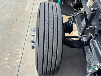 Peterbilt 389 wheel/tire close-up showing dual rear drive tires and suspension components in view.